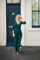 Female model in green wrap jumpsuit outdoor. Front view