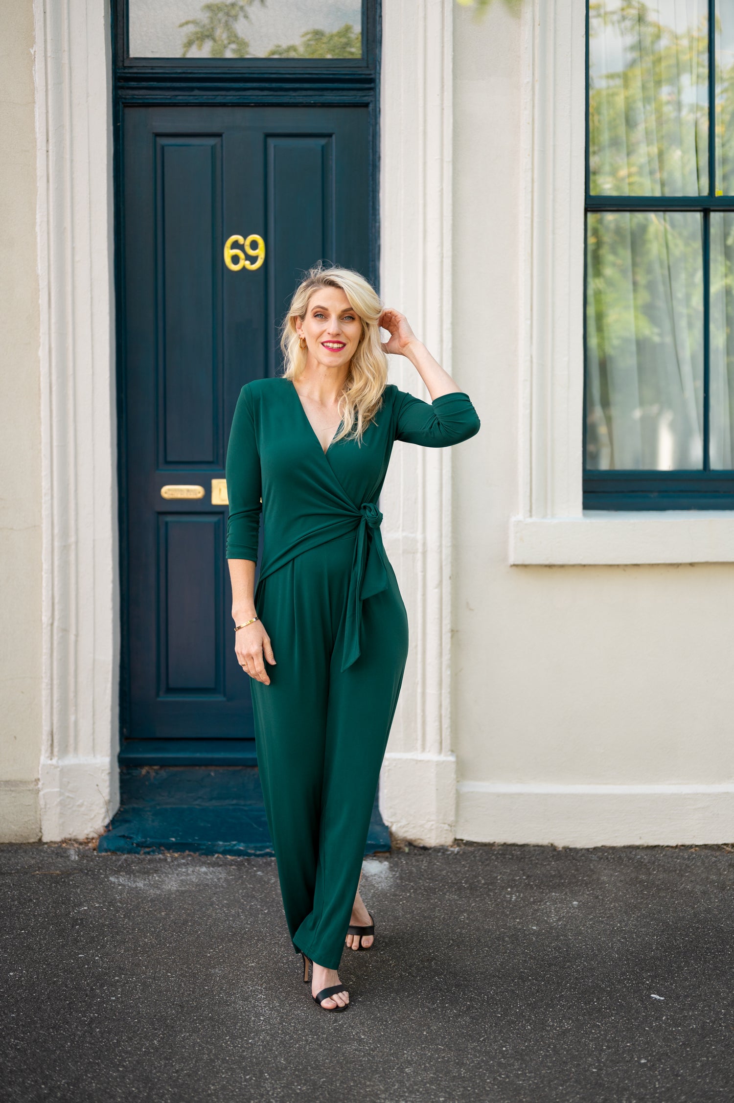 Female model in green wrap jumpsuit outdoor. Front view