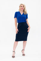 By Samantha Melbourne Officewear. Model wears Gina the V-neck blouse with flutter sleeve in cobalt blue with Andy pencil skirt in knee-length in navy. The blouse is tucked into skirt