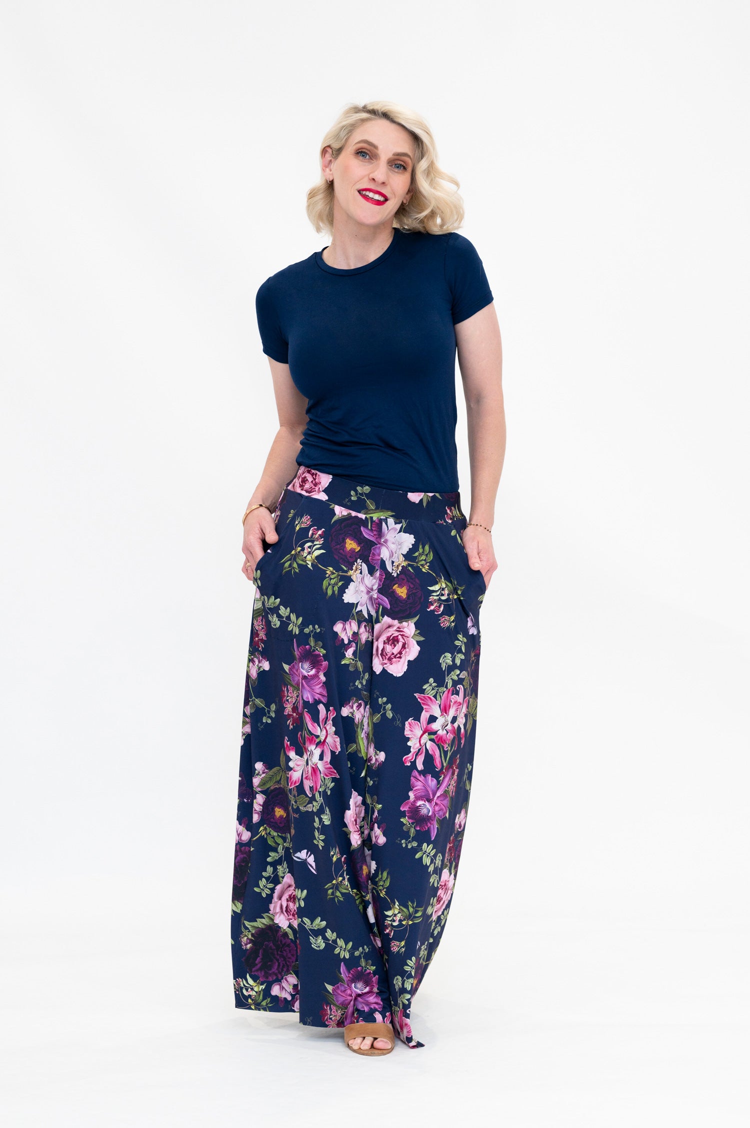 Model wearing Hazel palazzo pants by By Samantha Melbourne. Wide-leg, high-waisted style with pockets in a navy floral print with pink accents.