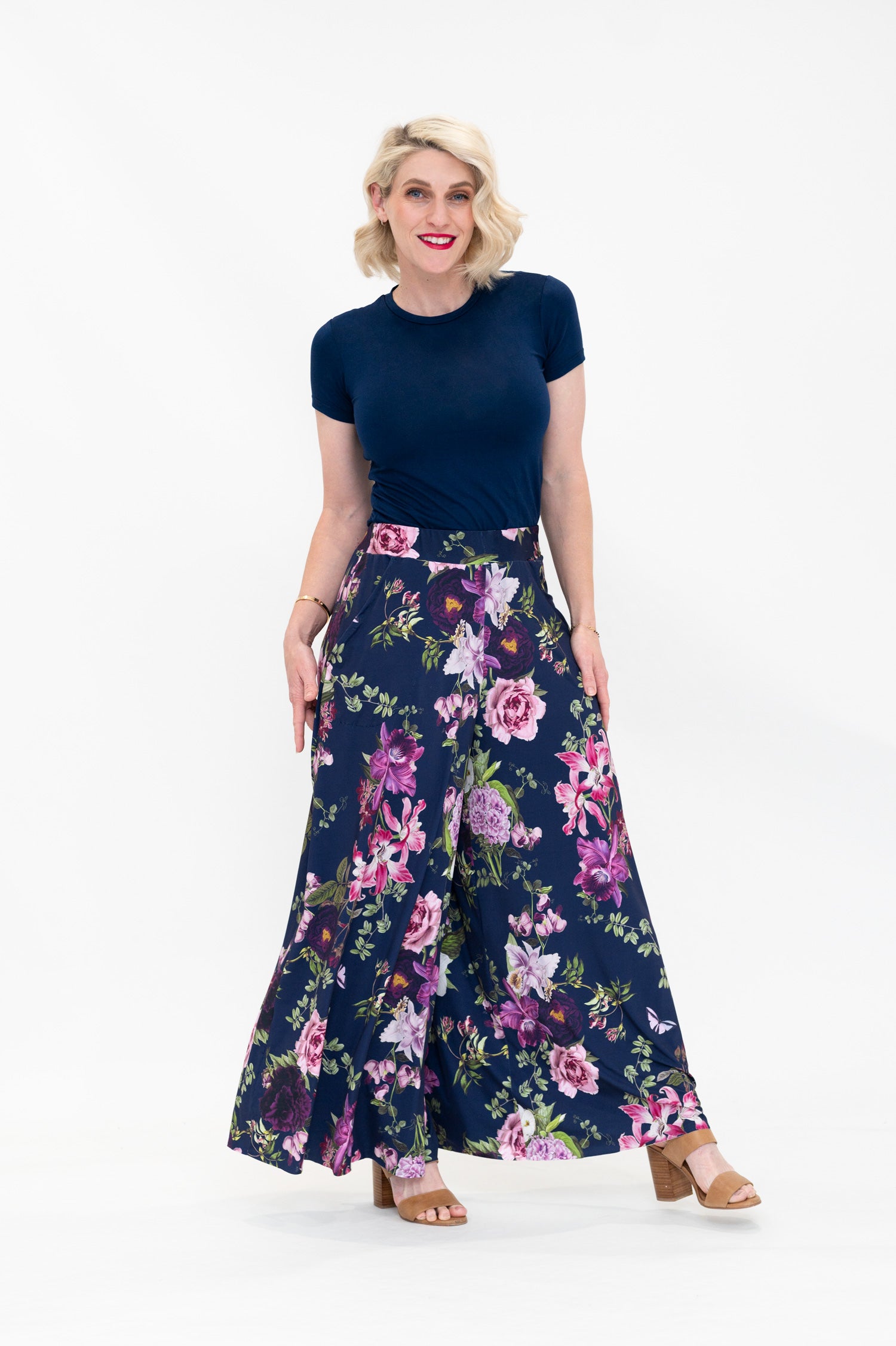 Model wearing Hazel palazzo pants by By Samantha Melbourne. Wide-leg, high-waisted style with pockets in a navy floral print with pink accents.