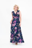 Model wearing the Hazel sleeveless maxi floral wrap dress by By Samantha Melbourne. Curve-friendly fit with a deep navy base and pink botanical print.