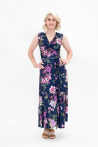 Model wearing the Hazel sleeveless midi floral wrap dress by By Samantha Melbourne. Curve-friendly fit with a deep navy base and pink botanical print.