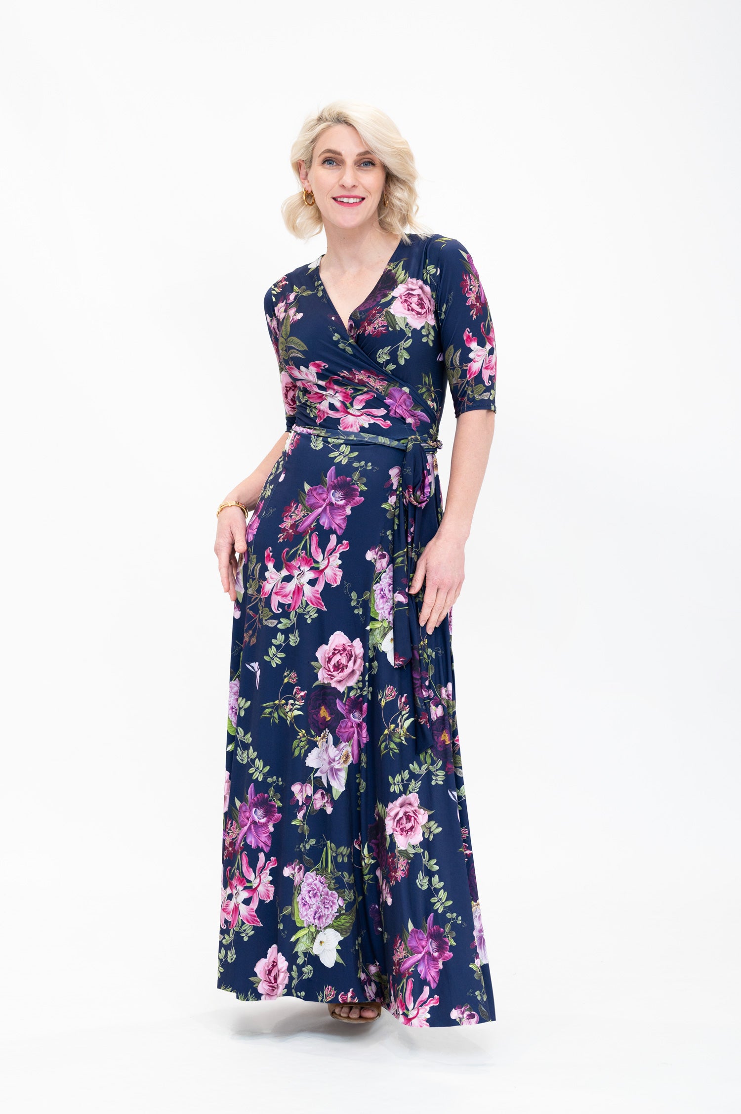 Model wearing the Hazel maxi floral wrap dress with 3/4 sleeves by By Samantha Melbourne. Curve-friendly fit with a deep navy base and pink botanical print.