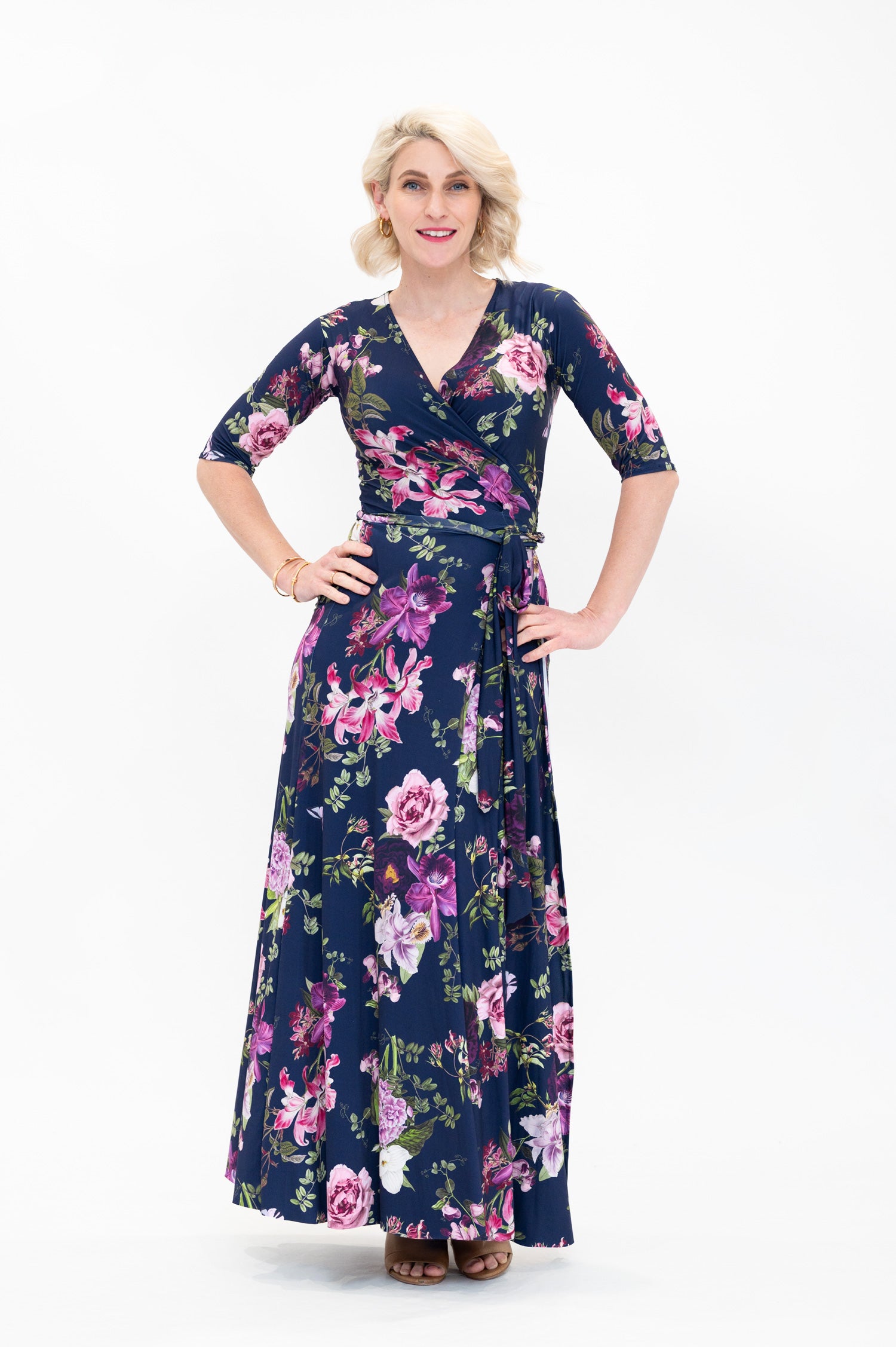 Model wearing the Hazel maxi floral wrap dress with 3/4 sleeves by By Samantha Melbourne. Curve-friendly fit with a deep navy base and pink botanical print.
