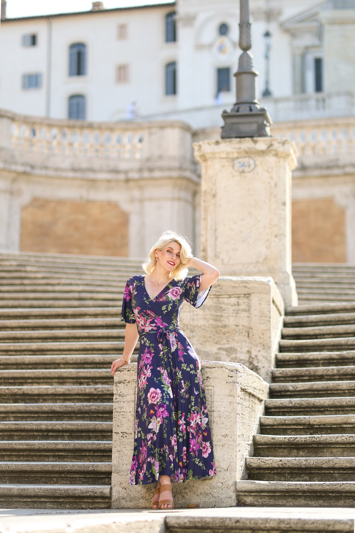 Model wearing the Hazel floral wrap dress by By Samantha Melbourne. Curve-friendly fit with a deep navy base and pink botanical print.