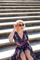 Model wearing the Hazel floral wrap dress by By Samantha Melbourne. Curve-friendly fit with a deep navy base and pink botanical print.