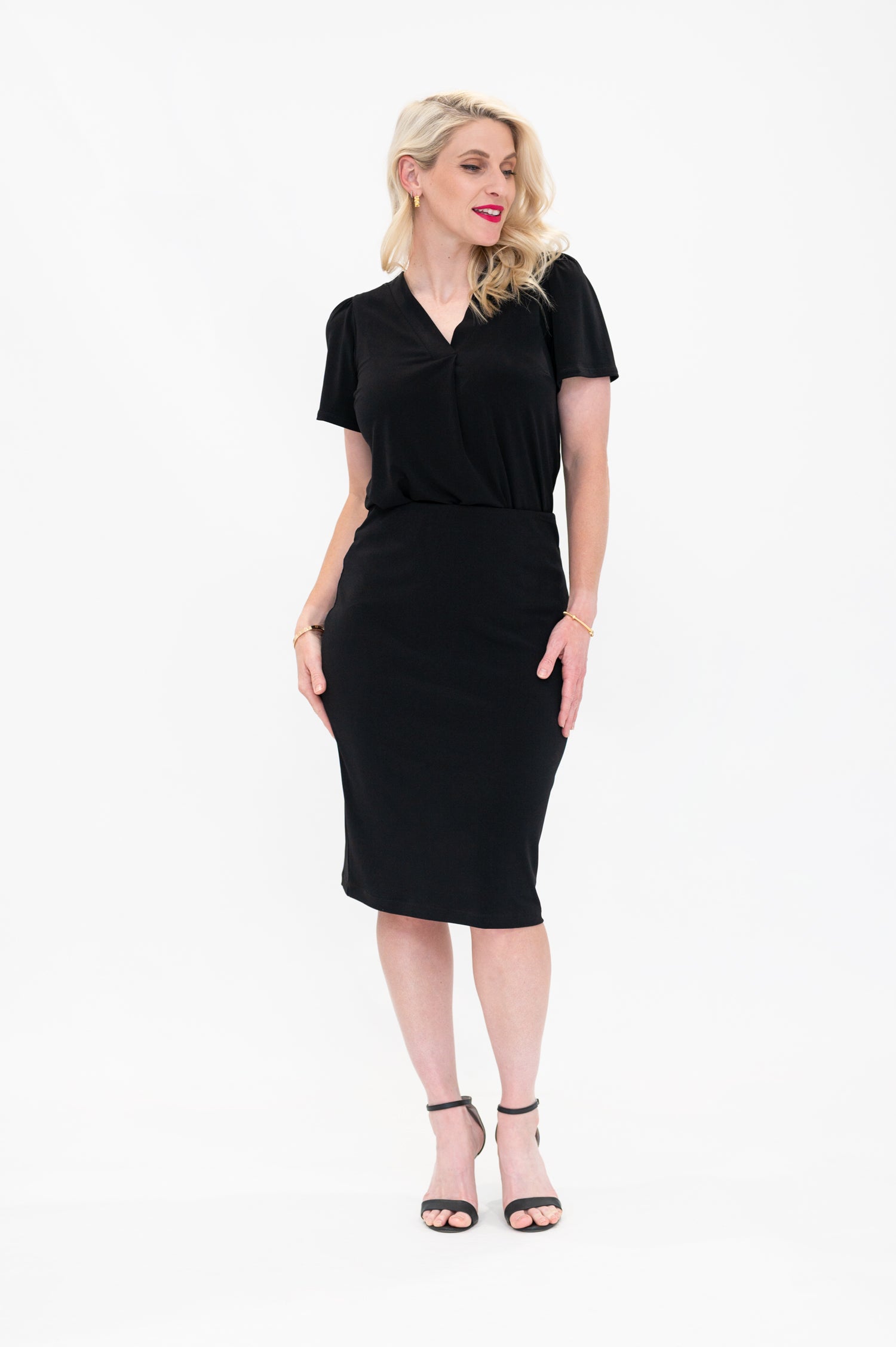 By Samantha Melbourne Officewear. Model wears Gina the V-neck blouse with flutter sleeve in black with Andy pencil skirt in knee-length in black
