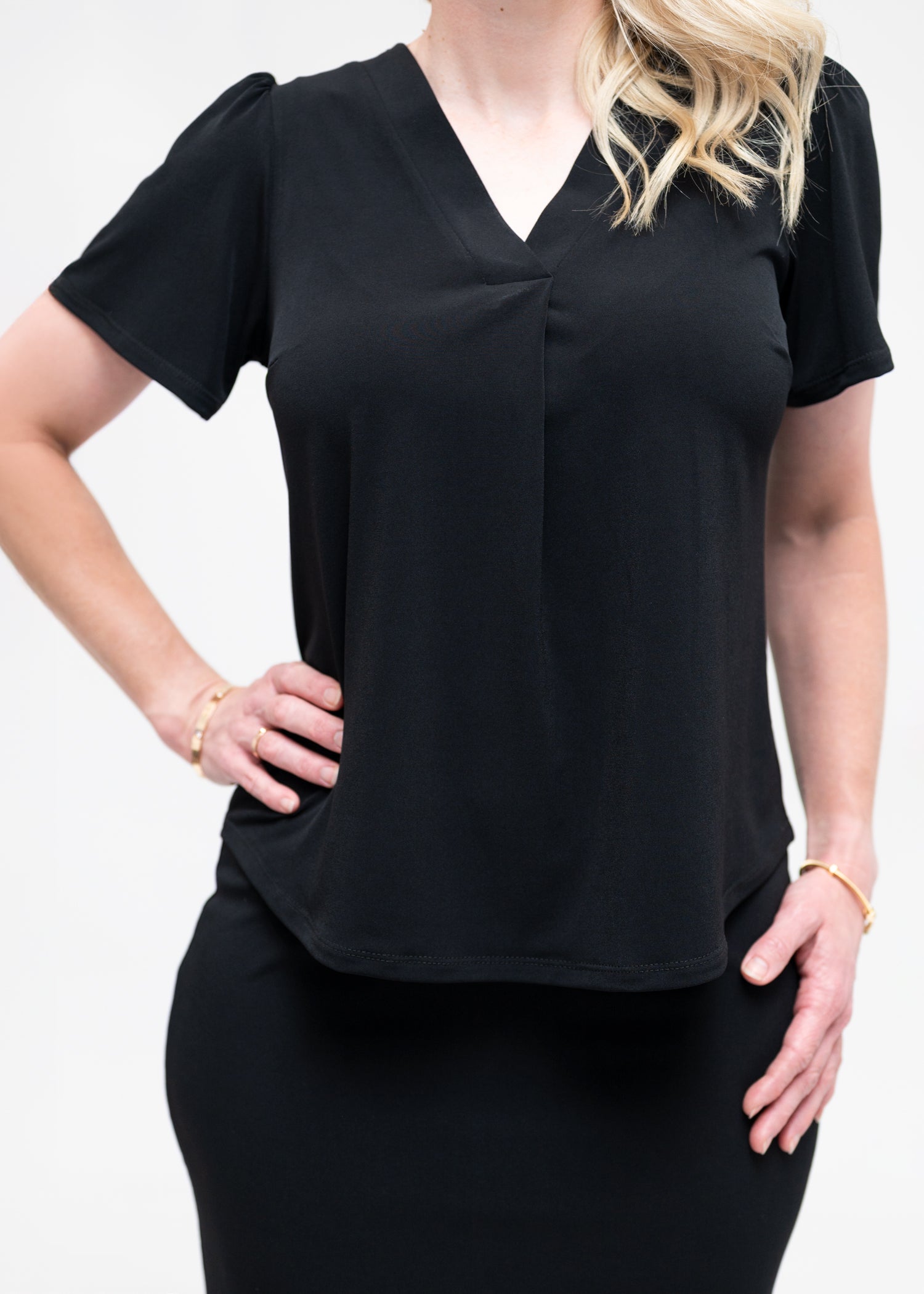 By Samantha Melbourne Officewear. Model wears Gina the V-neck blouse with flutter sleeve in black with Andy pencil skirt in knee-length in black. Closeup of the Gina v-neck blouse