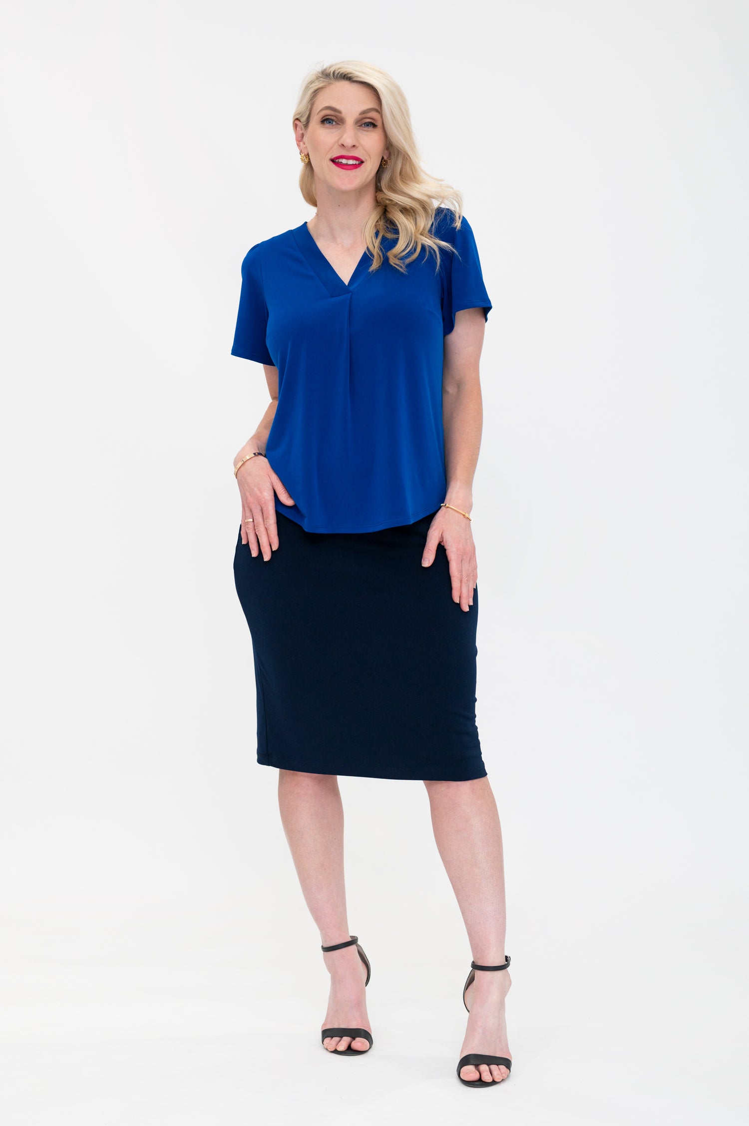 By Samantha Melbourne Officewear. Model wears Gina the V-neck blouse with flutter sleeve in cobalt blue with Andy pencil skirt in knee-length in navy. Blouse is untucked