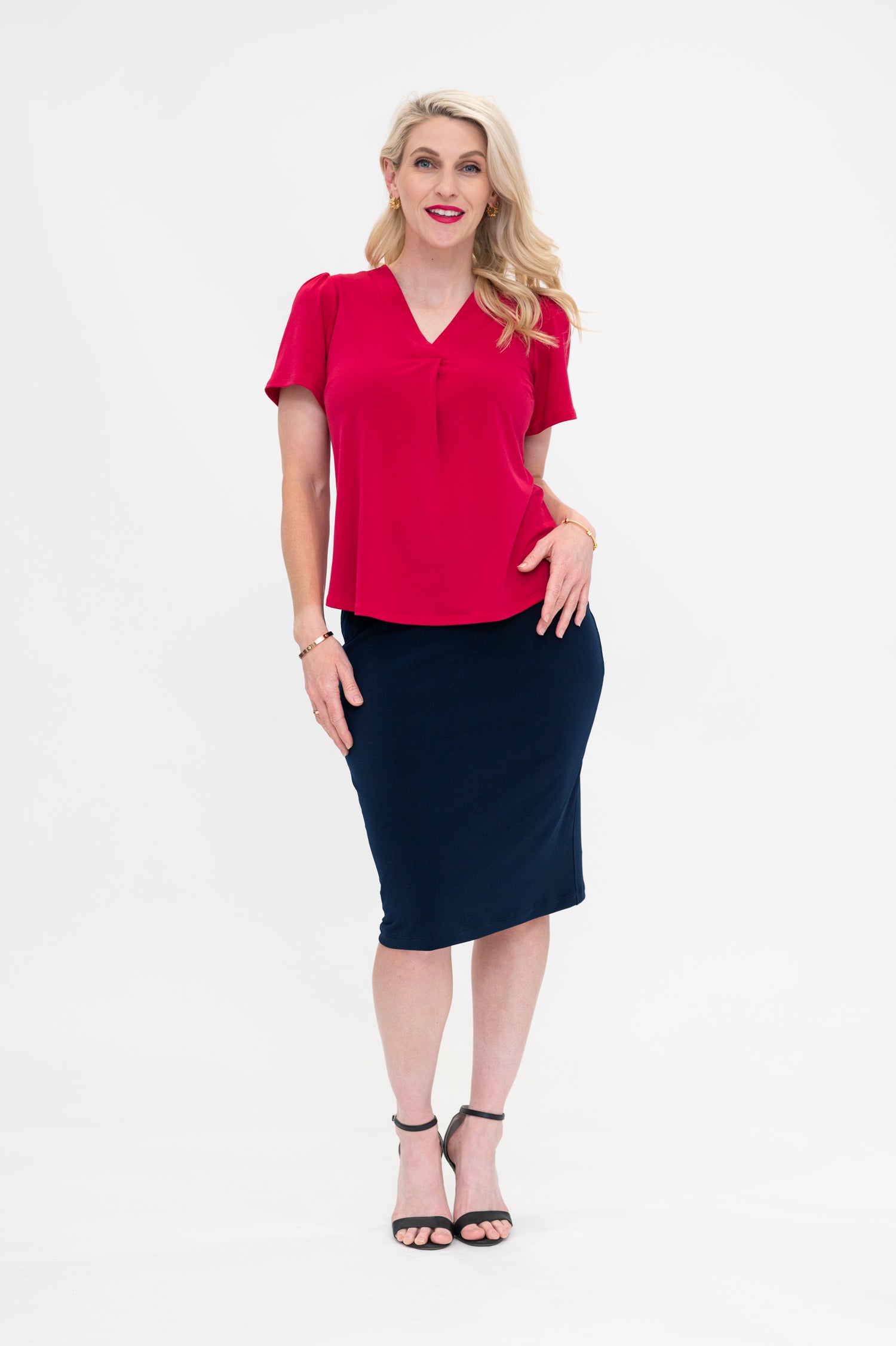 By Samantha Melbourne Officewear. Model wears Gina the V-neck blouse with flutter sleeve in granita raspberry red colour with Andy pencil skirt in knee-length in navy. The blouse is untucked