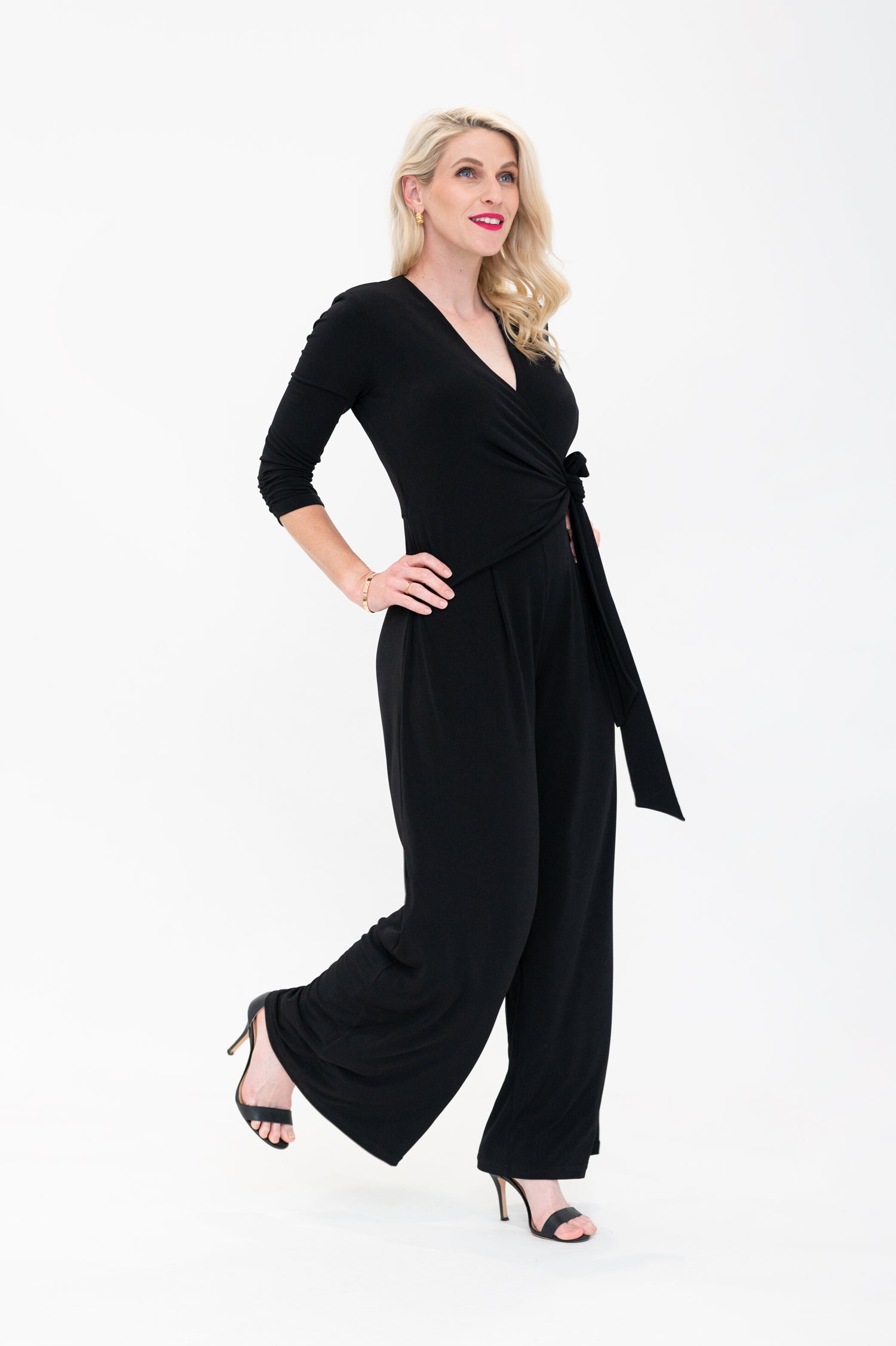 Female model in black wrap jumpsuit. Side view