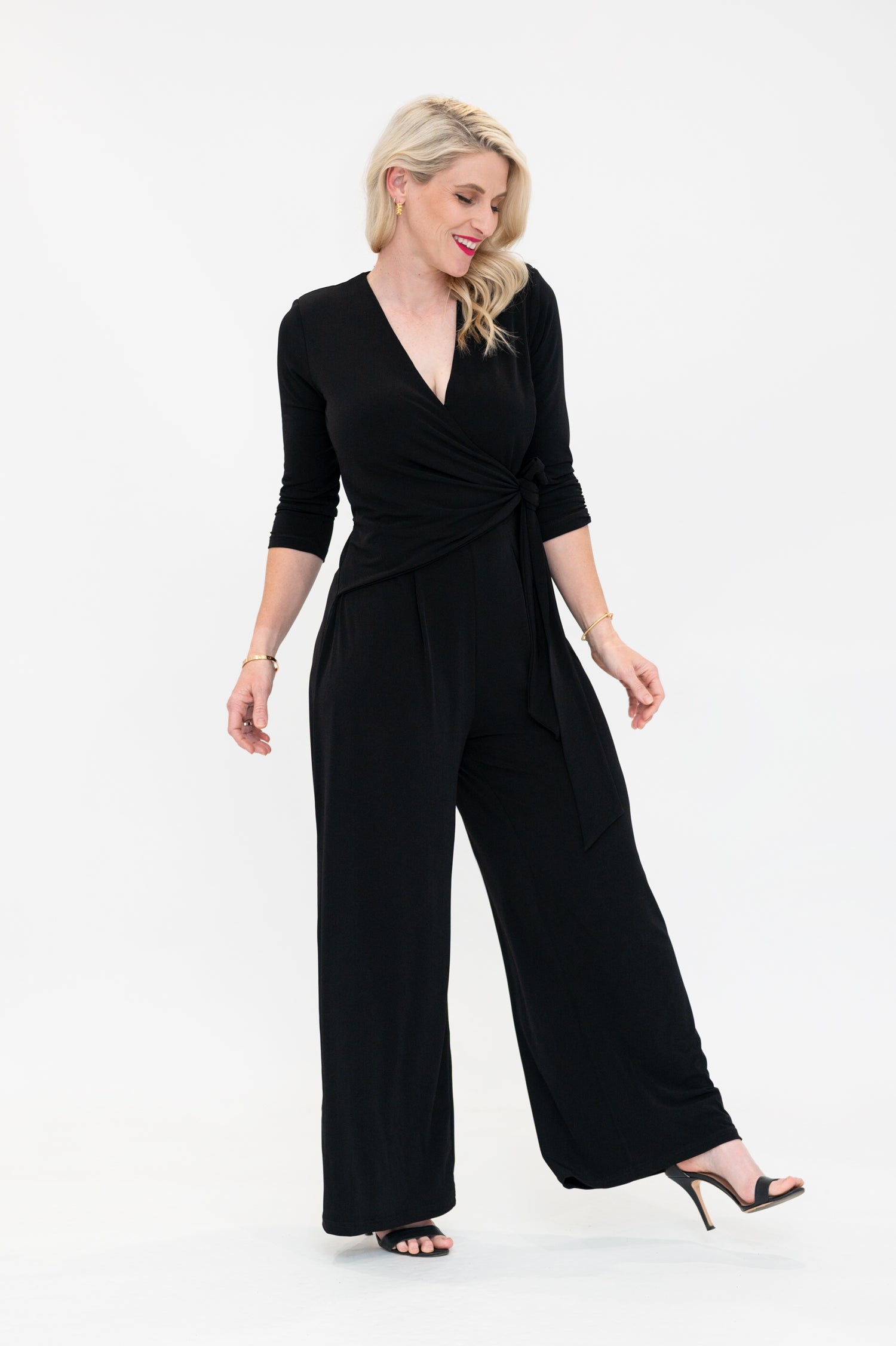 Female model in black wrap jumpsuit. Side view