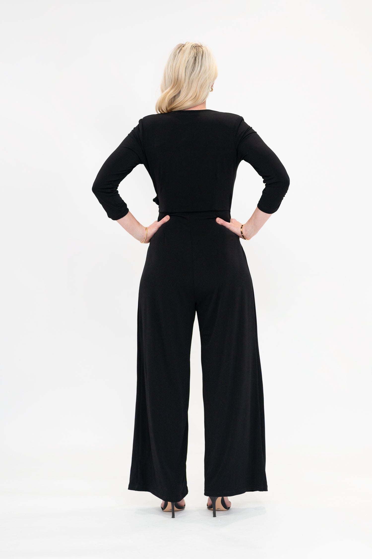 Female model in black wrap jumpsuit. Back view
