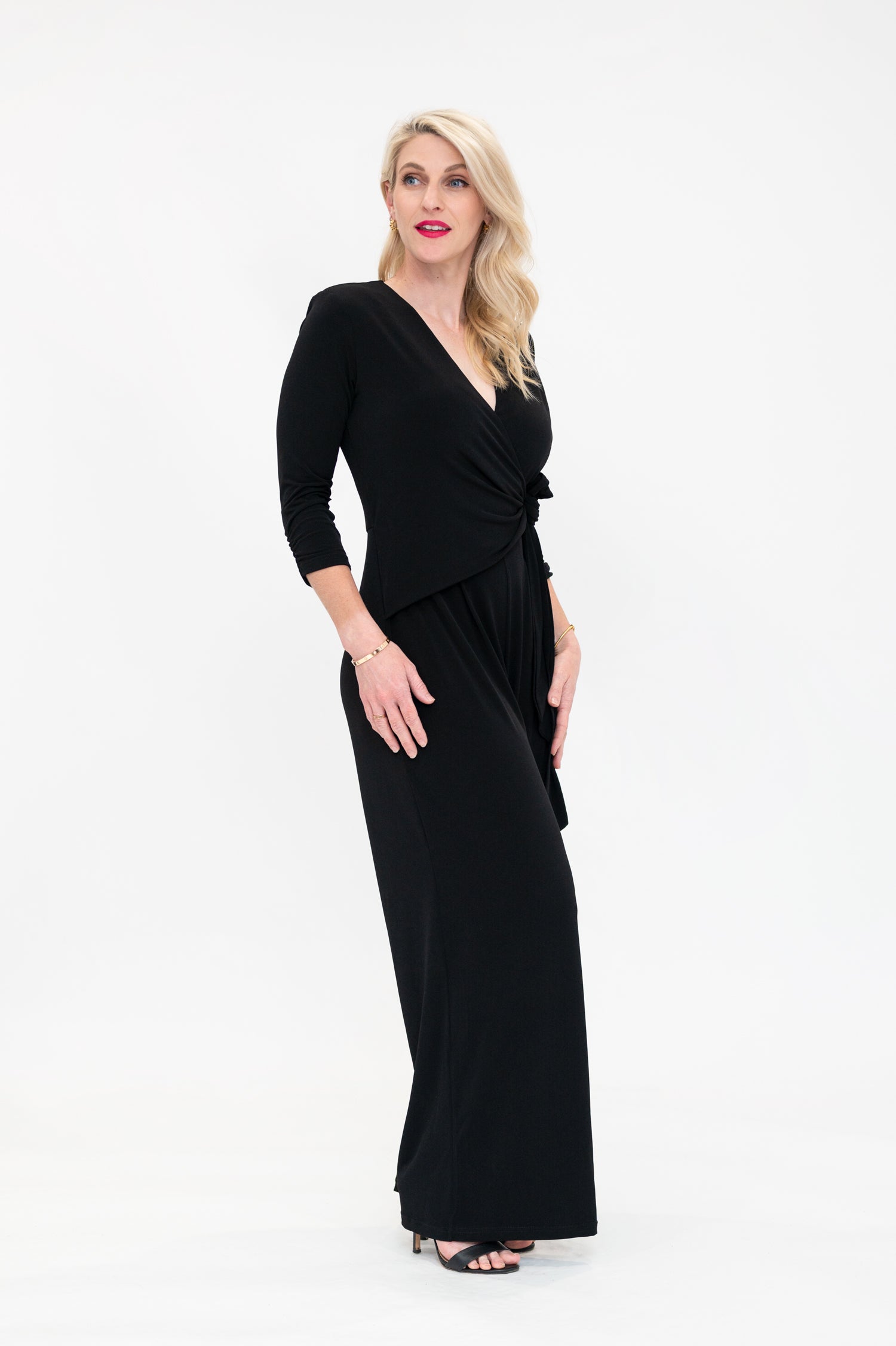 Female model in black wrap jumpsuit. Side view