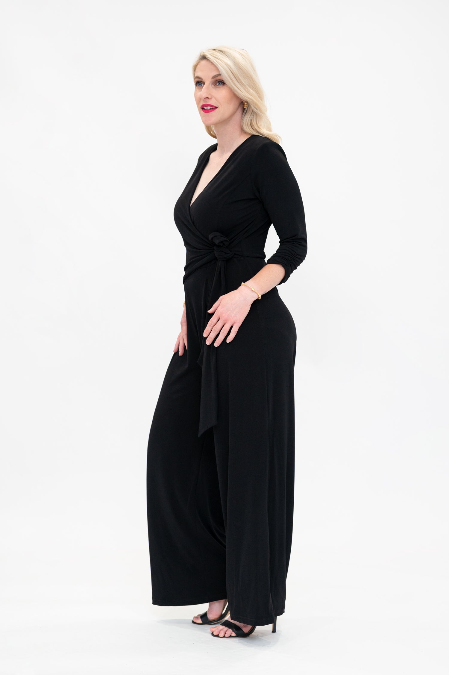 Female model in black wrap jumpsuit. Side view