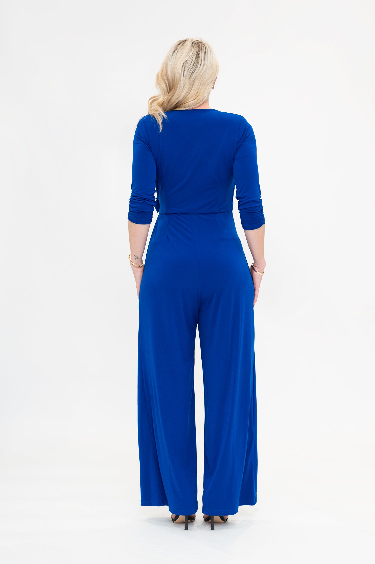 Female model in cobalt blue wrap jumpsuit. Back view