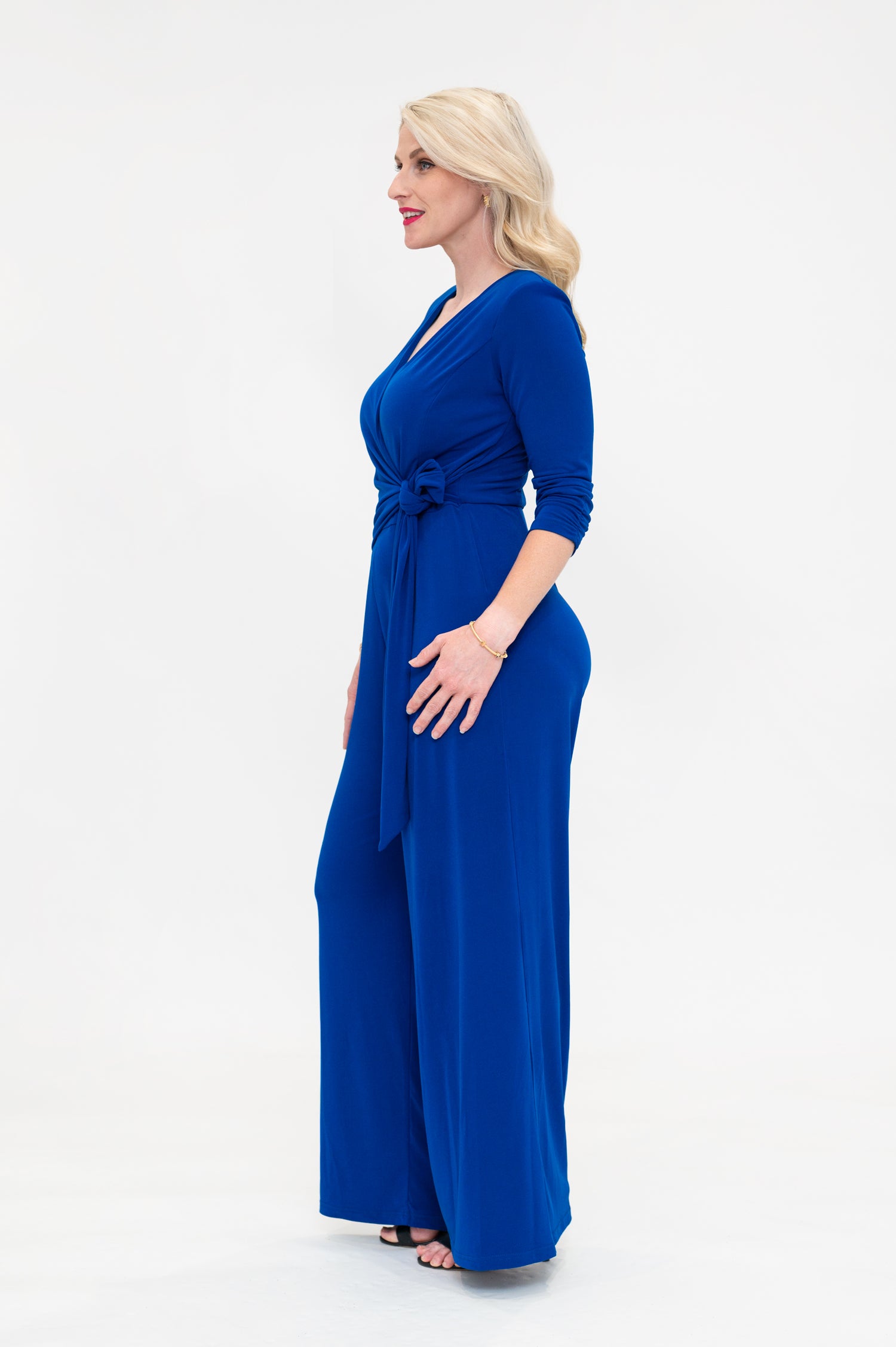 Female model in cobalt blue wrap jumpsuit. Side view