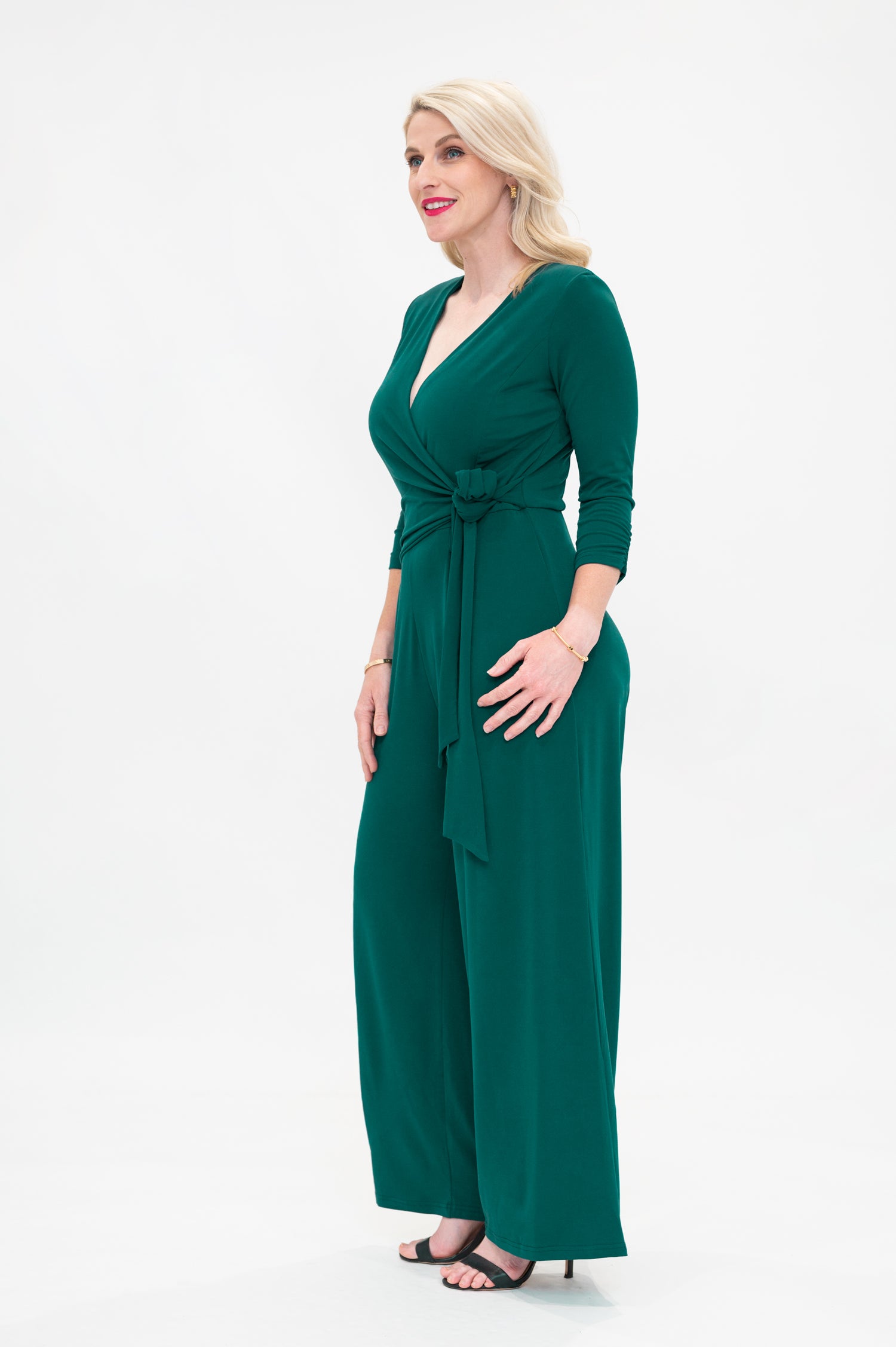 Female model in green wrap jumpsuit. Side view