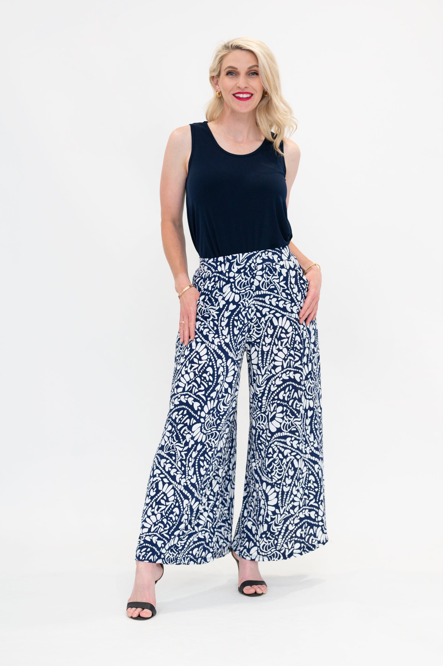 Female model wears Erin Singlet in the Navy colour. Erin Singlet is sleeveless, features Round Crew Neck, Swing style and Relaxed fit, Hip length. Singlet is tucked into By Samantha Melbourne Palazzo Pants