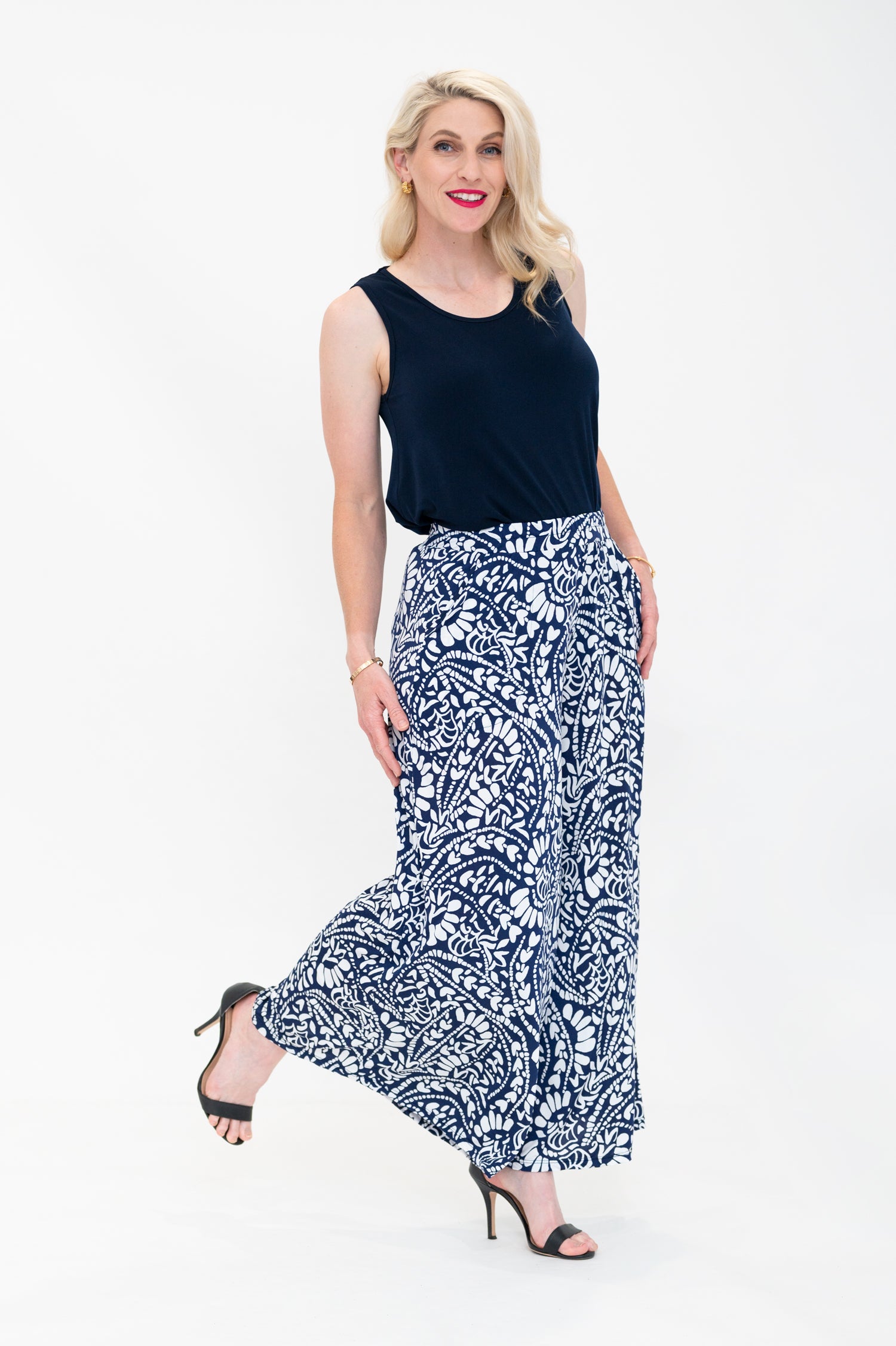 Female model wears Erin Singlet in the Navy colour. Erin Singlet is sleeveless, features Round Crew Neck, Swing style and Relaxed fit, Hip length. Singlet is tucked into By Samantha Melbourne Palazzo Pants Side View