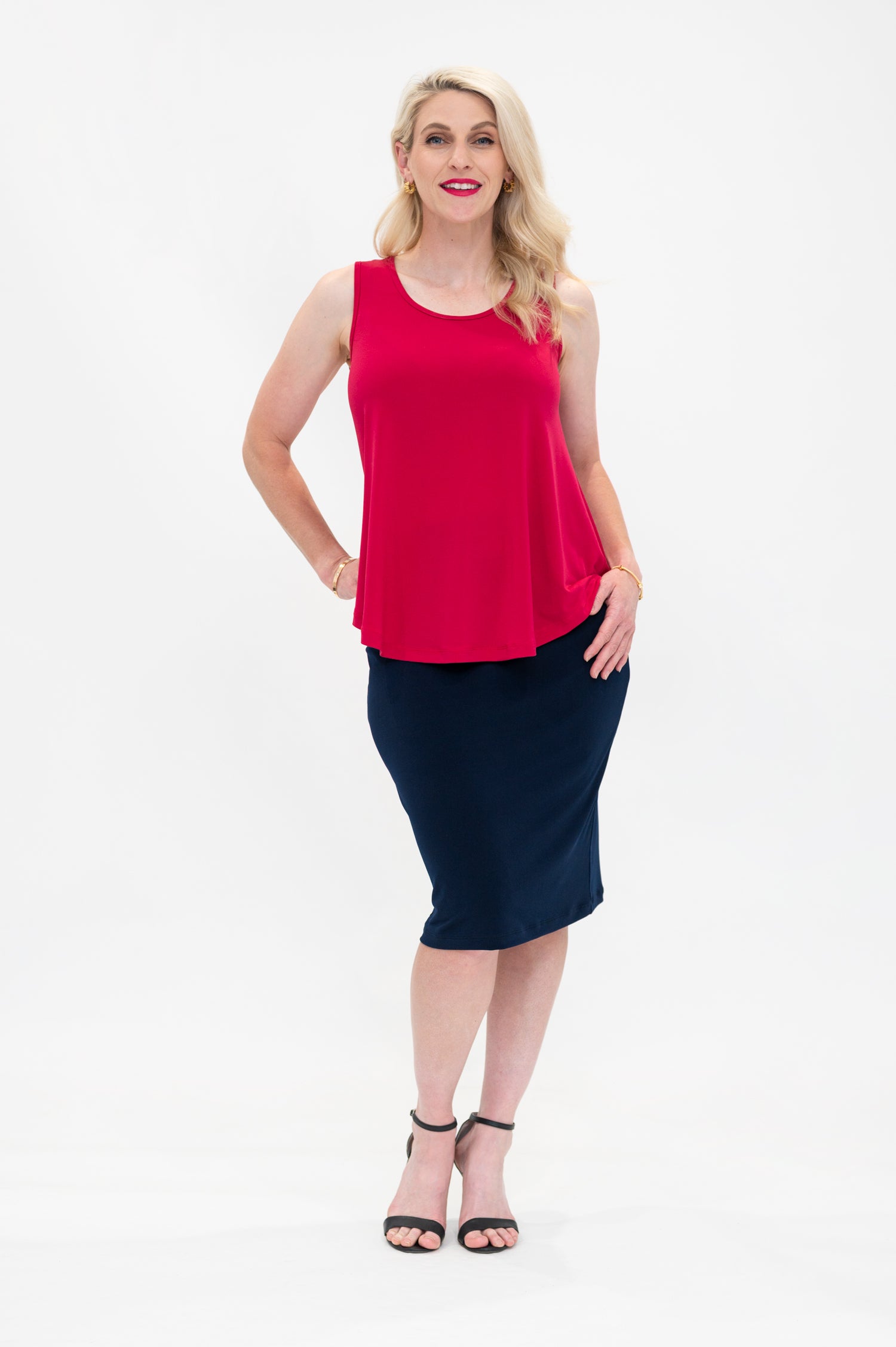 By Samantha Melbourne Erin Swing Singlet. Available in 3 colours. Made in Australia. Model wears Erin Singlet in Red. Erin Singlet is sleeveless, features Round Crew Neck, Swing style and Relaxed fit, Hip length. Singlet is untucked and is paired with By Samantha Melbourne Andy Pencil Skirt in Navy