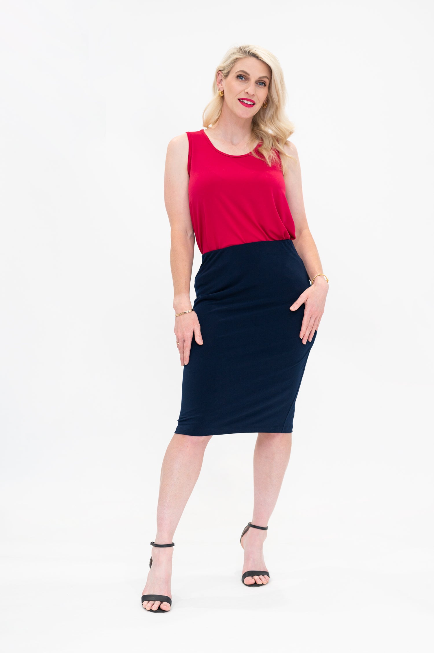 By Samantha Melbourne Erin Swing Singlet. Available in 3 colours. Made in Australia. Model wears Erin Singlet in Red. Erin Singlet is sleeveless, features Round Crew Neck, Swing style and Relaxed fit, Hip length. Singlet is tucked into By Samantha Melbourne Andy Pencil Skirt in Navy