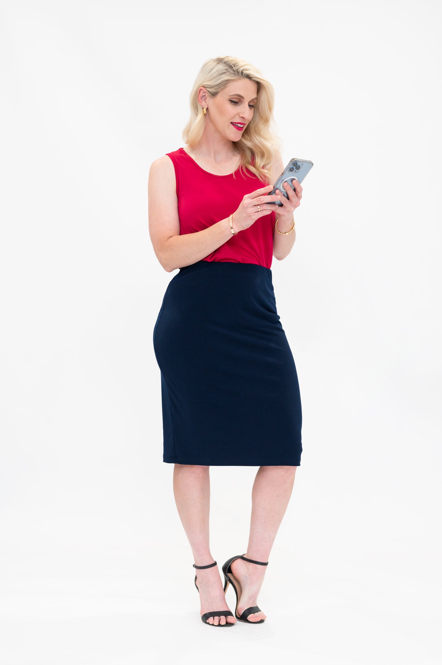 By Samantha Melbourne Erin Swing Singlet. Available in 3 colours. Made in Australia. Model wears Erin Singlet in Red. Erin Singlet is sleeveless, features Round Crew Neck, Swing style and Relaxed fit, Hip length. Singlet is tucked into By Samantha Melbourne Andy Pencil Skirt in Navy