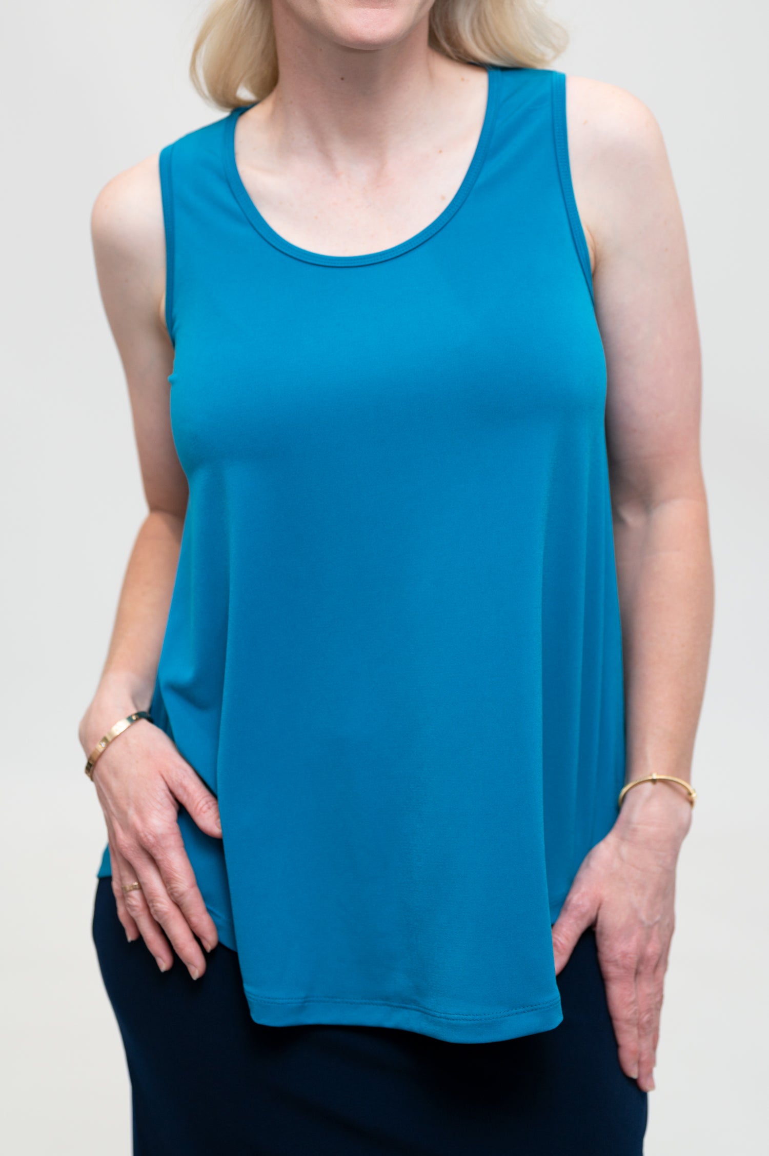 By Samantha Melbourne Erin Swing Singlet. Available in 3 colours. Made in Australia. Model wears Erin Singlet in Blue. Erin Singlet is sleeveless, features Round Crew Neck, Swing style and Relaxed fit, Hip length. Singlet is untucked and paired with By Samantha Melbourne Andy Pencil Skirt in Navy