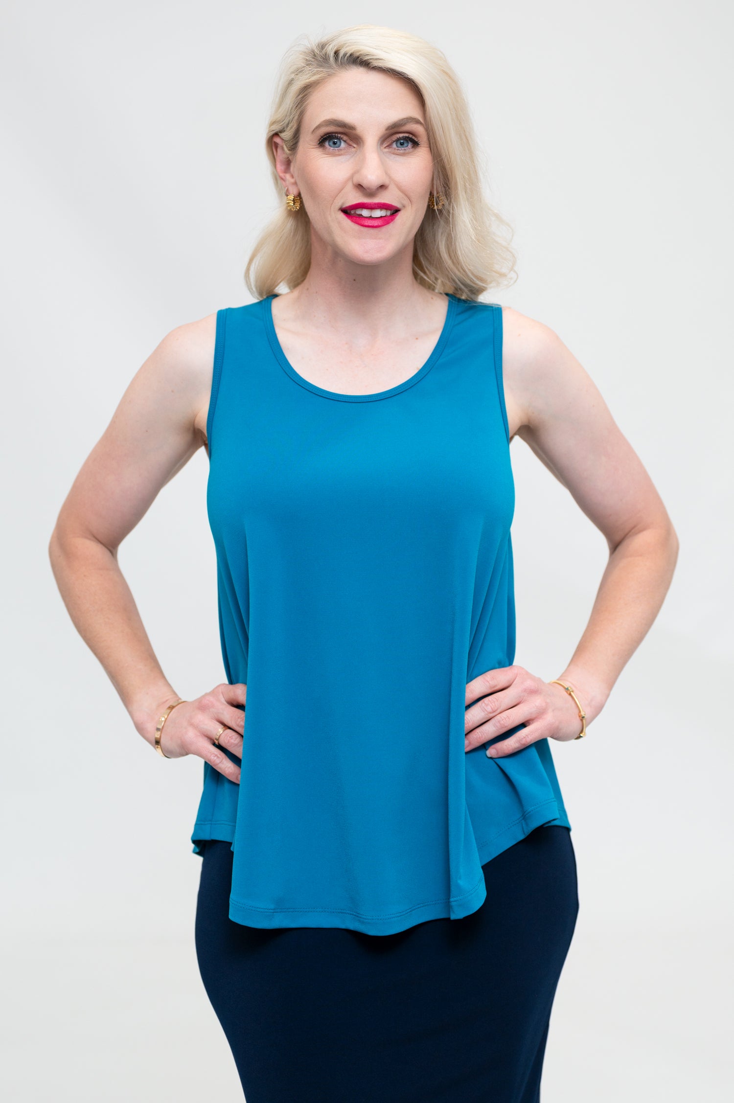 By Samantha Melbourne Erin Swing Singlet. Available in 3 colours. Made in Australia. Model wears Erin Singlet in Blue. Erin Singlet is sleeveless, features Round Crew Neck, Swing style and Relaxed fit, Hip length. Singlet is untucked and paired with By Samantha Melbourne Andy Pencil Skirt in Navy