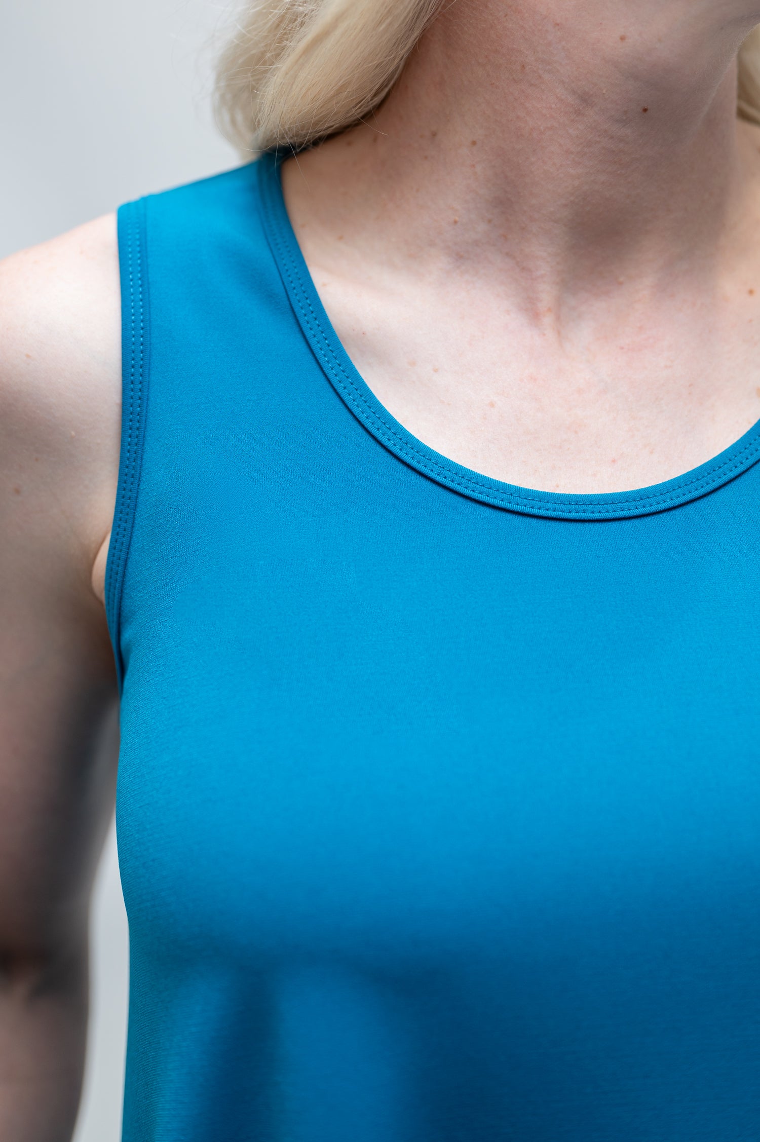 By Samantha Melbourne Erin Swing Singlet. Available in 3 colours. Made in Australia. Model wears Erin Singlet in Blue. Erin Singlet is sleeveless, features Round Crew Neck, Swing style and Relaxed fit, Hip length. Closeup