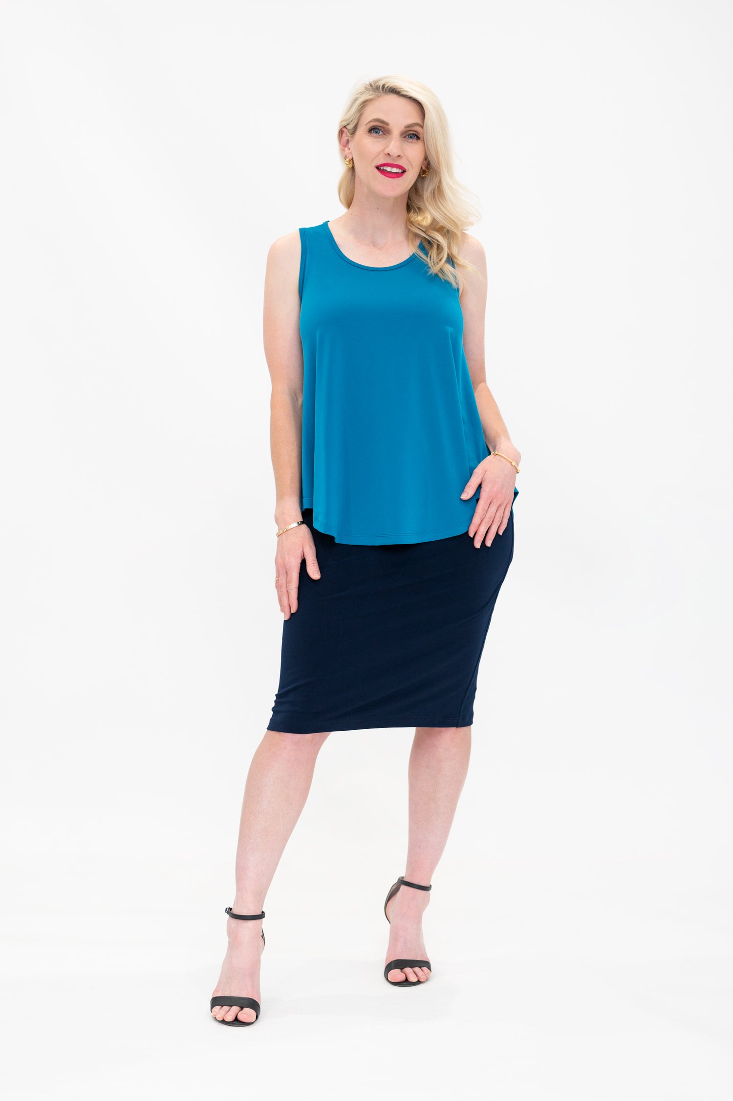 By Samantha Melbourne Erin Swing Singlet. Available in 3 colours. Made in Australia. Model wears Erin Singlet in Blue. Erin Singlet is sleeveless, features Round Crew Neck, Swing style and Relaxed fit, Hip length. Singlet is untucked and paired with By Samantha Melbourne Andy Pencil Skirt in Navy