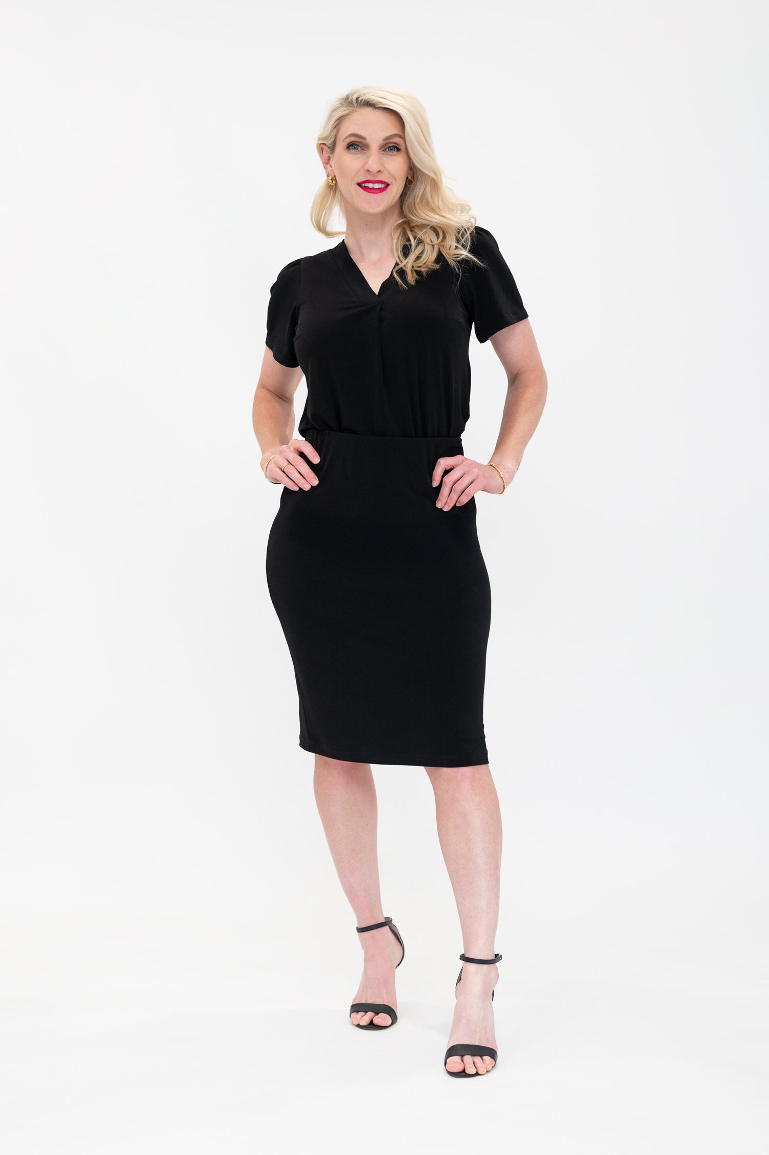 By Samantha Melbourne Officewear. Model wears Gina the V-neck blouse with flutter sleeve in black with Andy pencil skirt in knee-length in black. The blouse is tucked into skirt