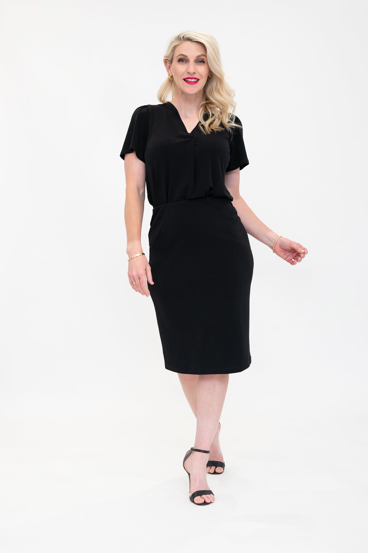 By Samantha Melbourne Officewear. Model wears Gina the V-neck blouse with flutter sleeve in black with Andy pencil skirt in knee-length in black. The blouse is tucked into skirt
