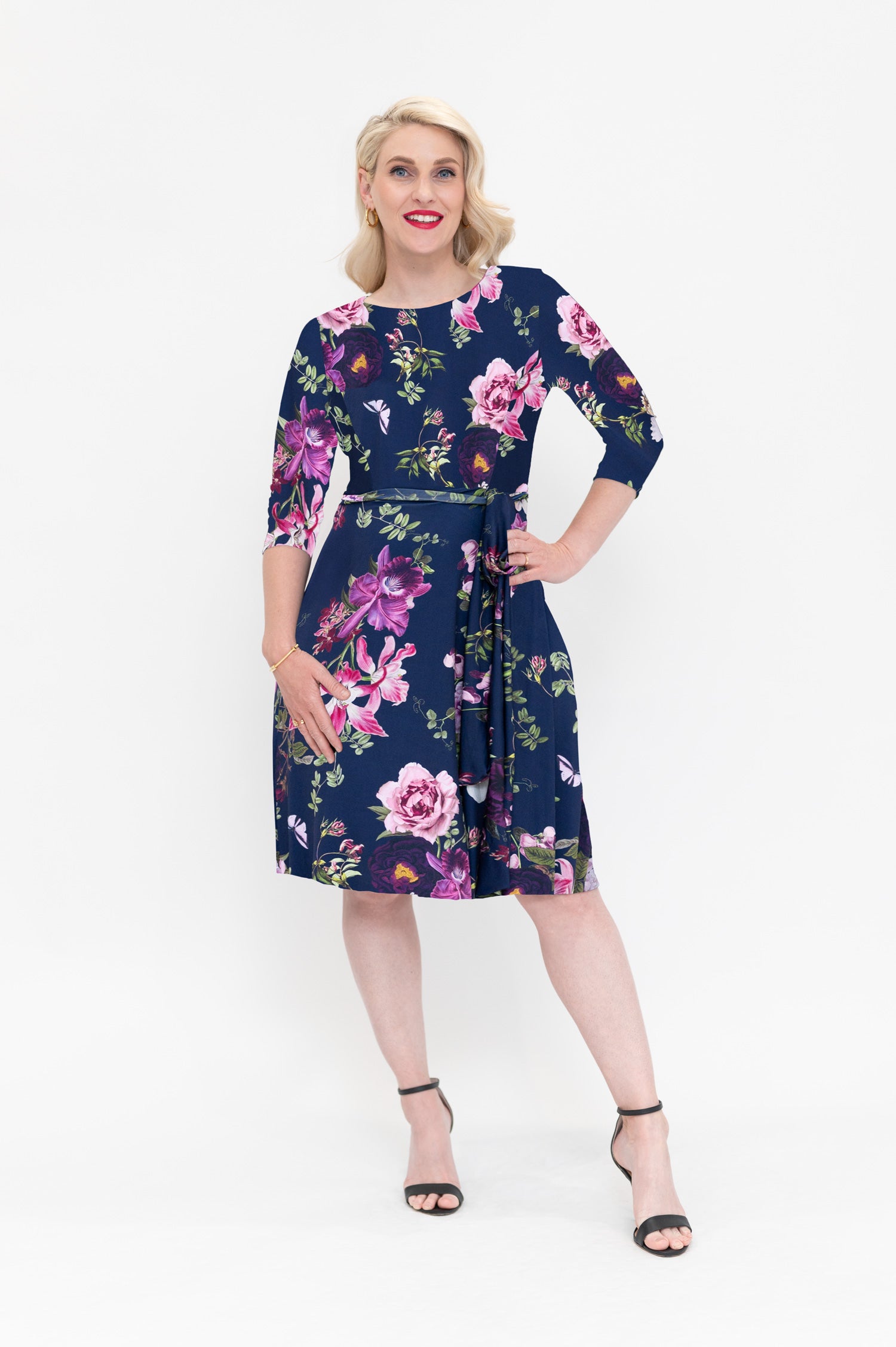 Model wearing the Hazel knee-length shift wrap dress with pockets by By Samantha Melbourne. Curve-friendly fit with a deep navy base and pink botanical print.
