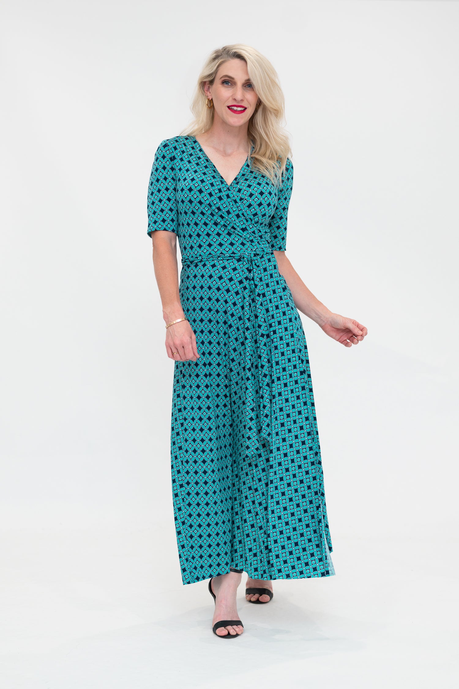 The female model wears a wrap dress in midi length (ankle length) with 3/4 sleeves. The print is a small-scale deep navy, white and teal geometric diamond shape pattern. Front view