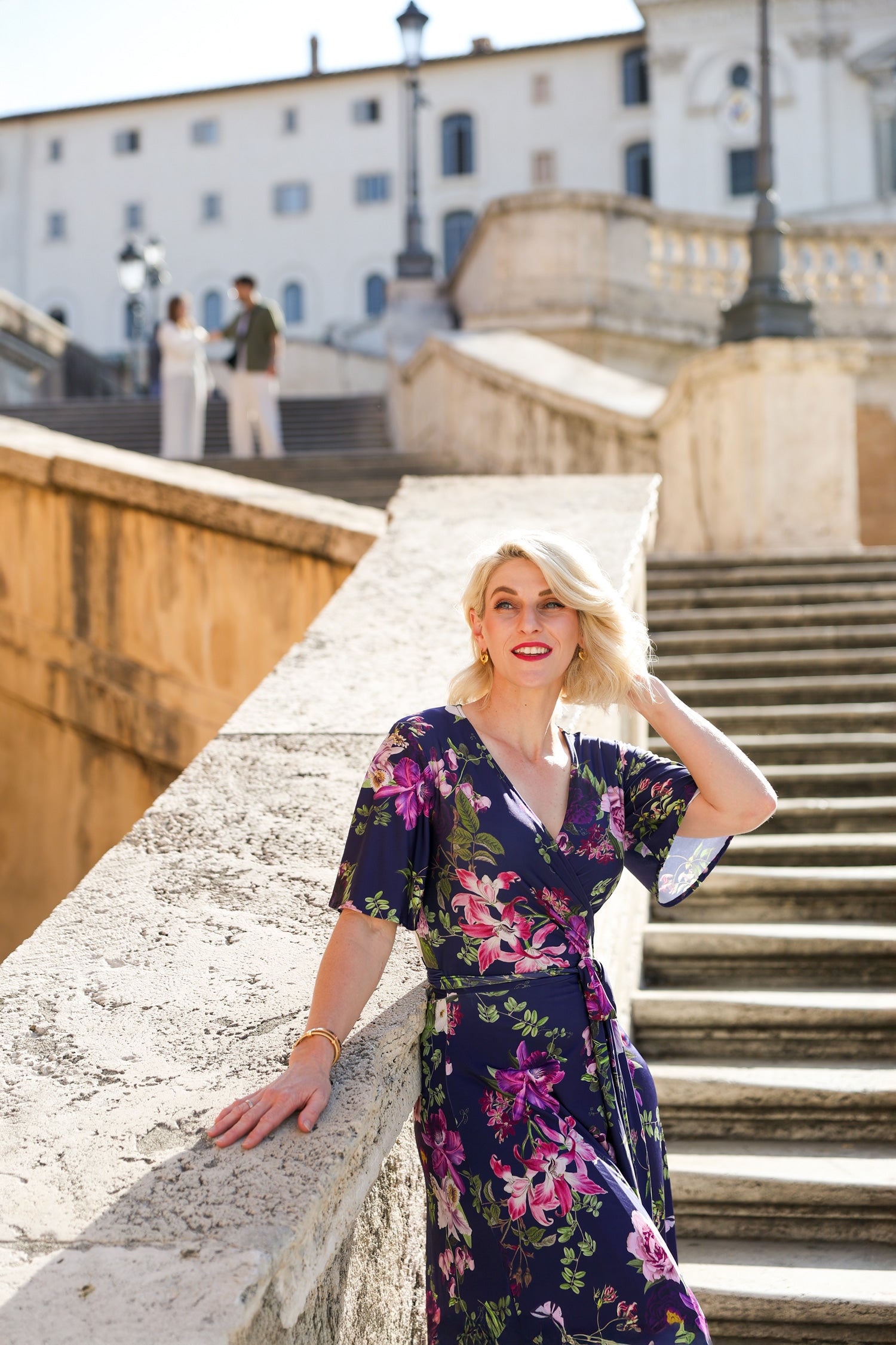 Model wearing the Hazel floral wrap dress by By Samantha Melbourne. Curve-friendly fit with a deep navy base and pink botanical print.